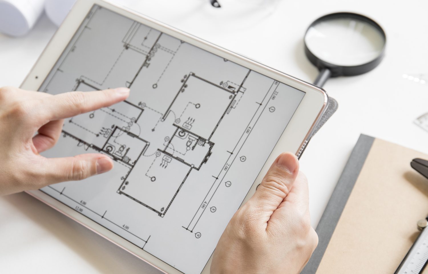 Persons hands holding tablet with construction building layout