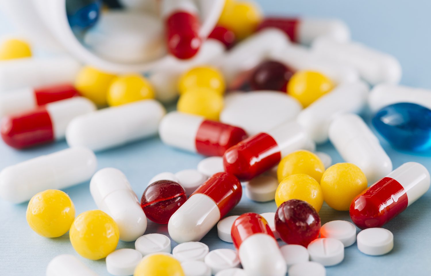 Red, white and yellow tablets and medication on table