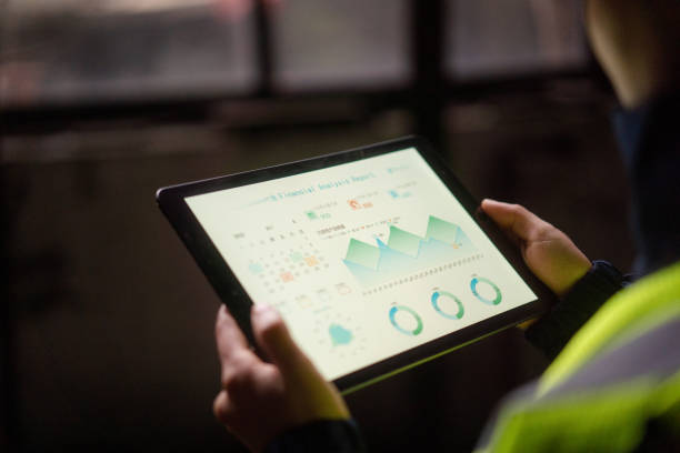 Engineers are using digital tablet to check statistical reports in the factory.